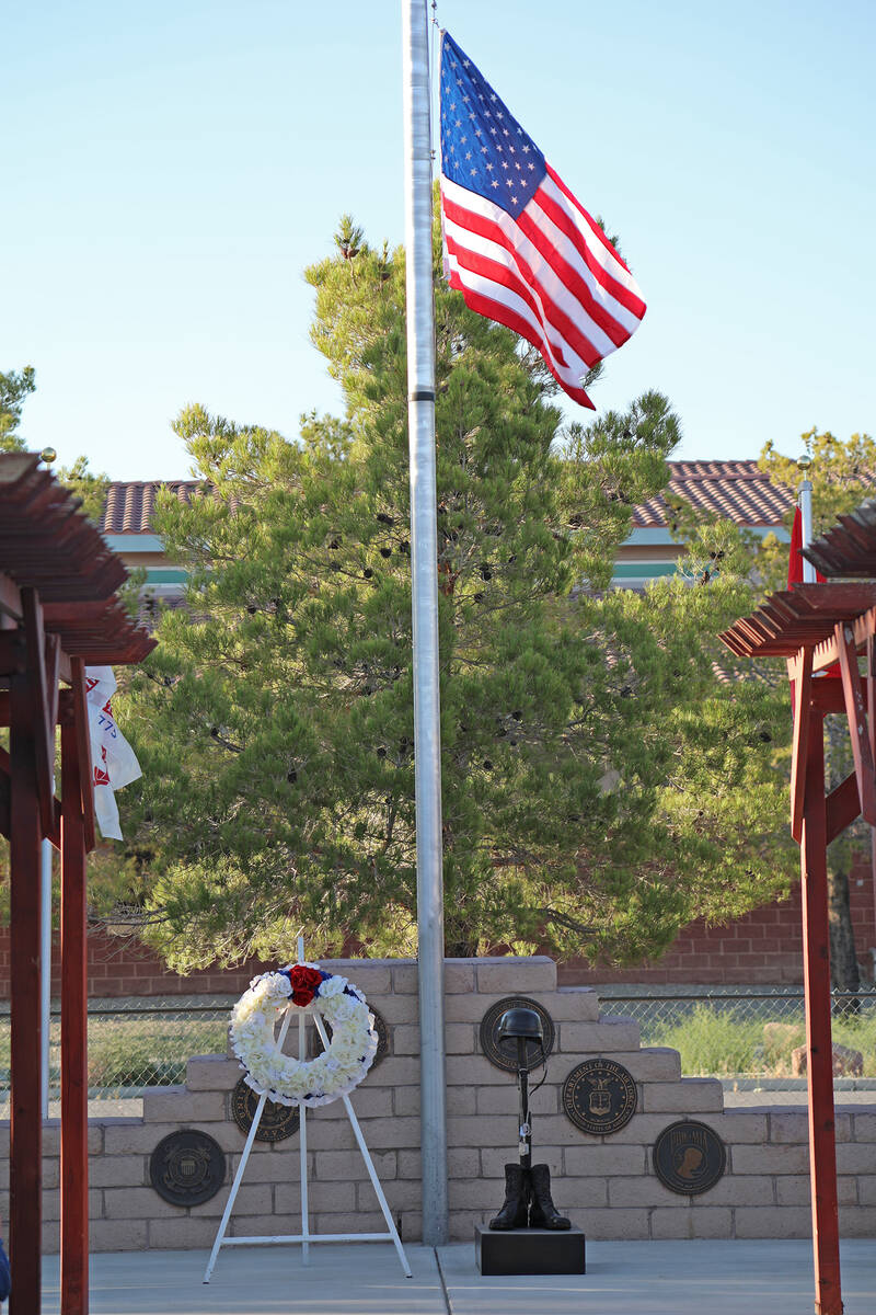 A white wreath sits beside the Battlefield Cross Statue as the American Flag floats in the ligh ...