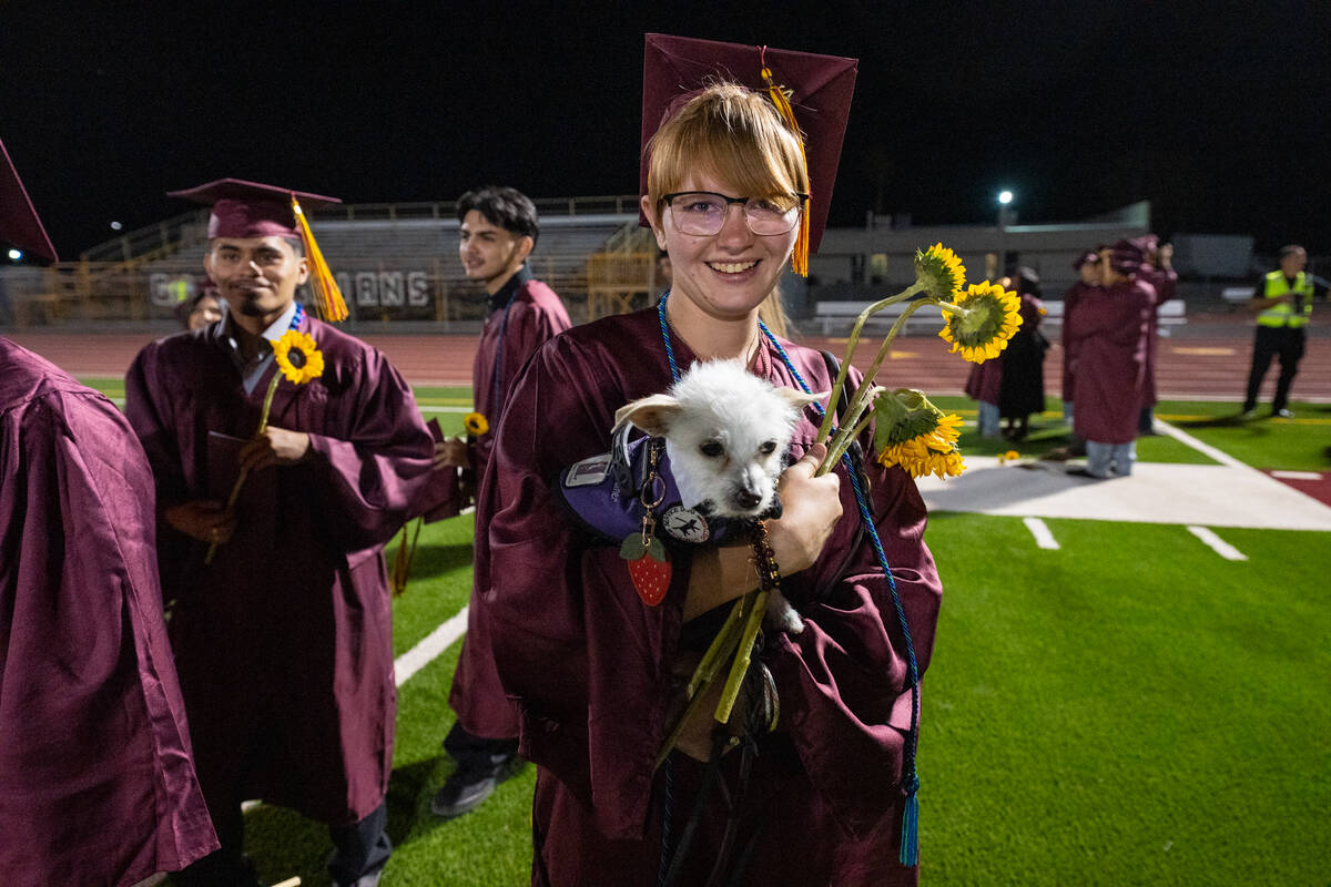 A graduate with her puppy picks up discarded flowers after the ceremony. (John Clausen/Pahrump ...