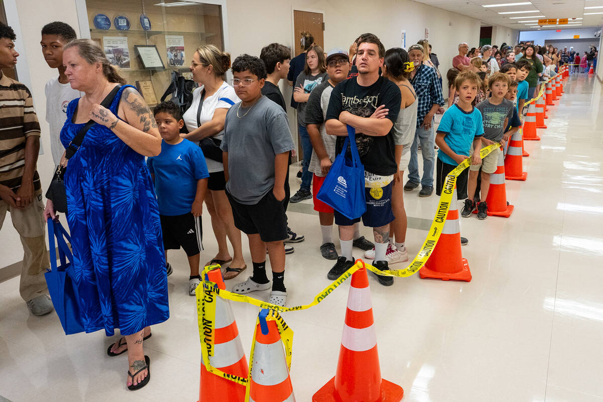 A long line of families waits inside the halls of Pahrump Valley High School for free backpacks ...