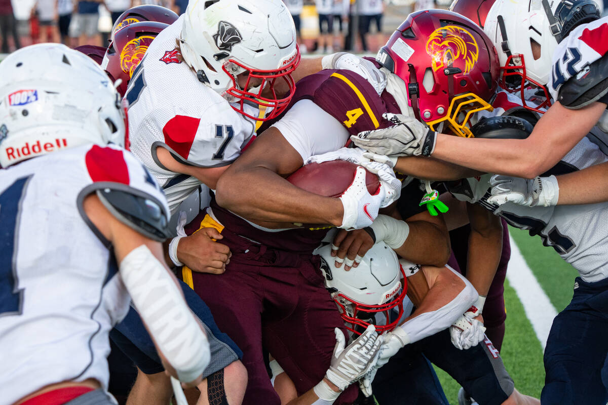 Pahrump Valley’s Iyan Bosket fights for yardage as Providence Hall defenders converge during ...