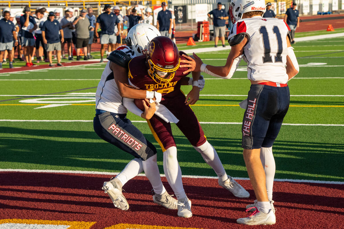 Pahrump Valley quarterback Evan Strain is wrapped up by Providence Hall defenders after carryin ...