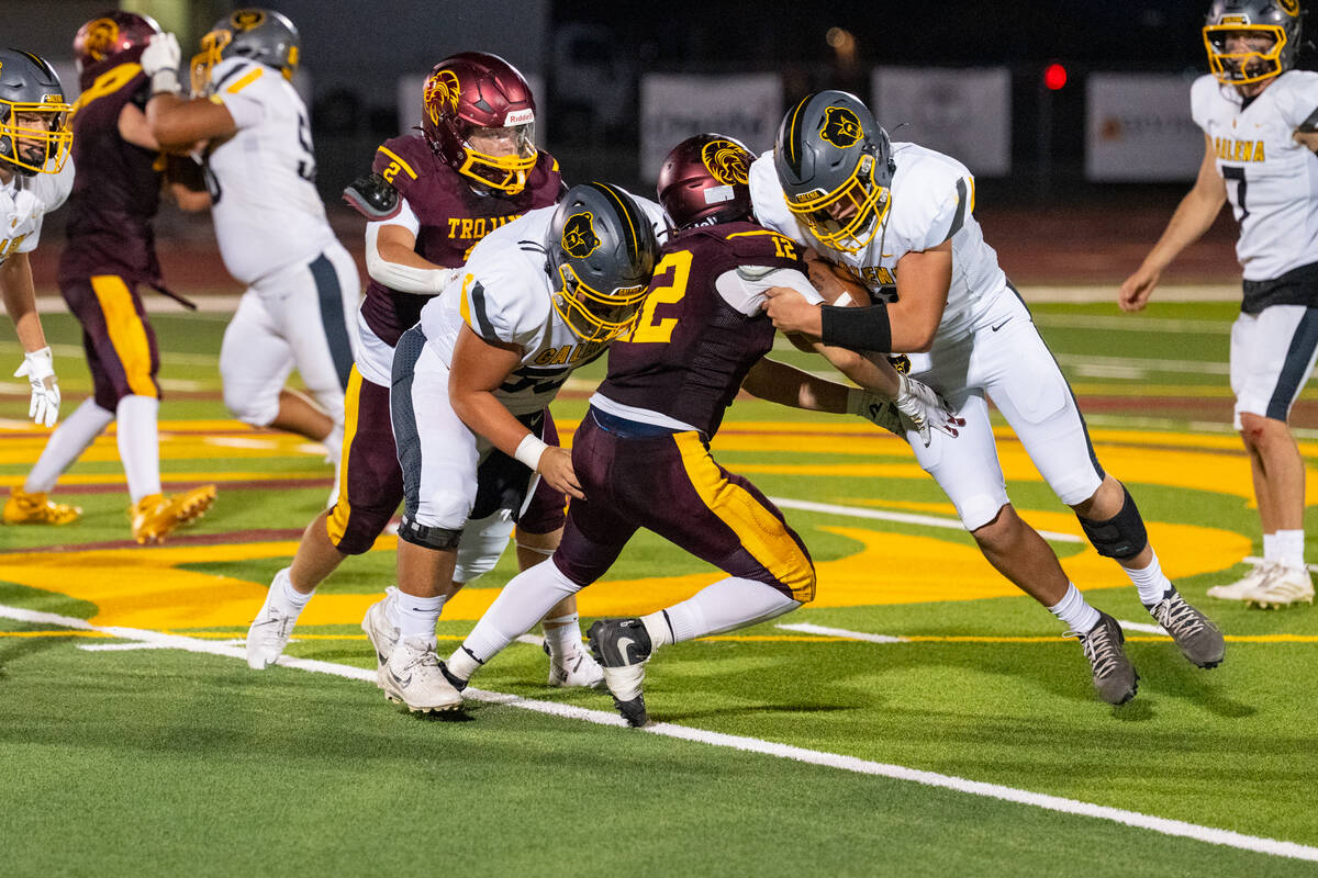 Pahrump Valley senior Preston Dockter fights through a pair of Galena defenders during the Troj ...