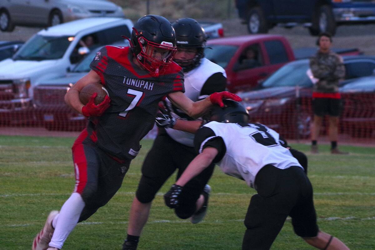 Tonopah senior Jacob Sprague uses a stiff-arm to turn away a Round Mountain defender during the ...