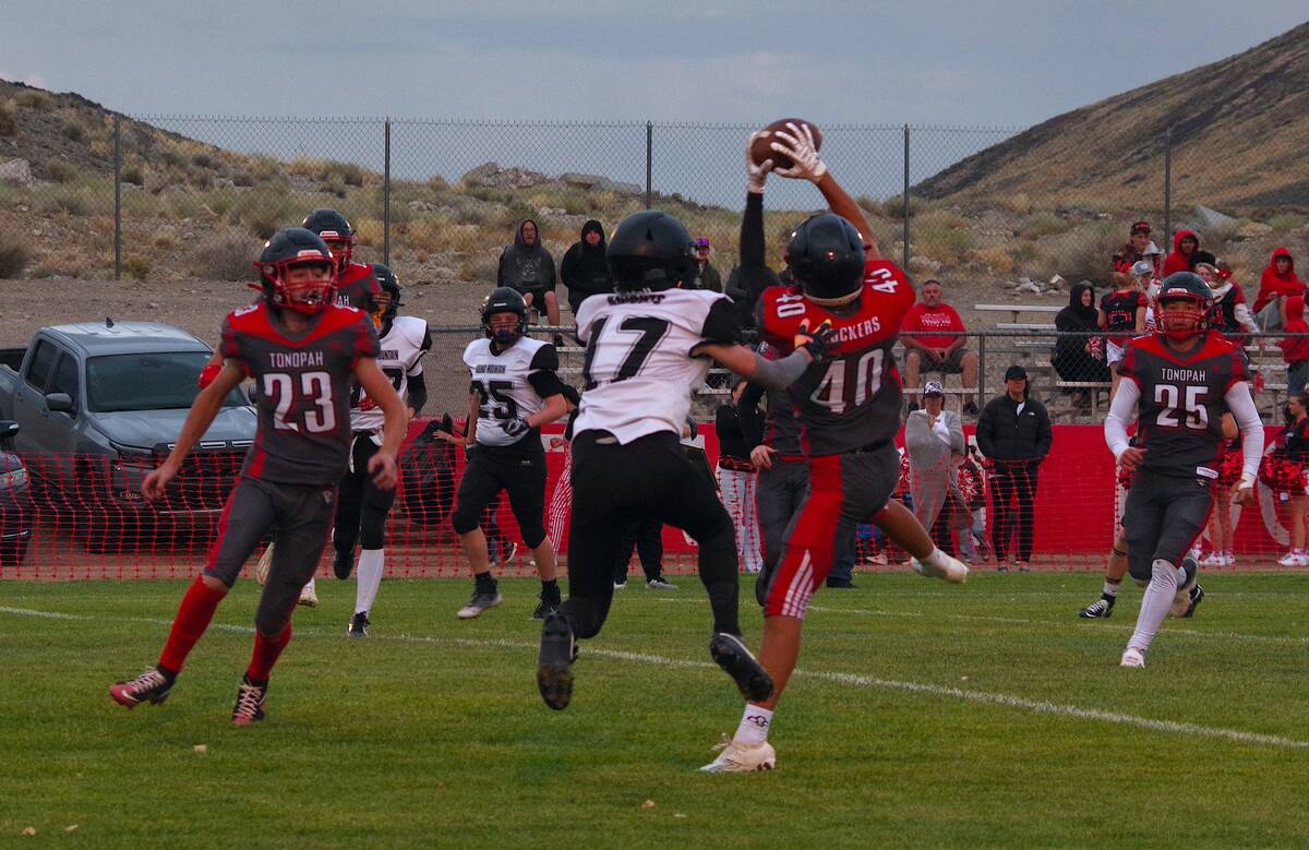 Tonopah sophomore Wyatt Miller (40) pressures a Round Mountain passer as junior Rustin Otteson ...