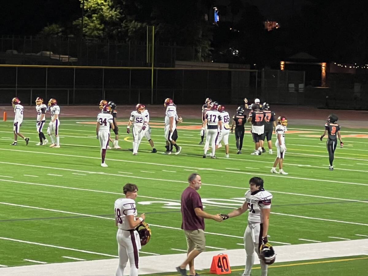 Pahrump Valley head coach Toby Henry shakes hands with Alejandro Rayas (51) as quarterback Evan ...
