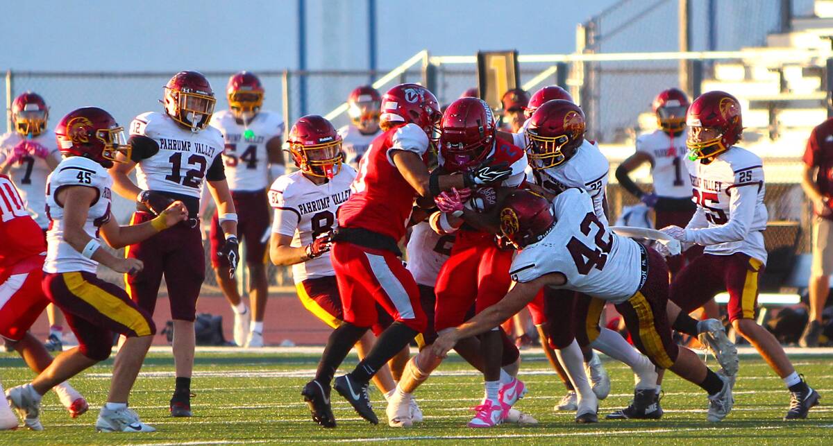 Pahrump Valley’s Christien Ramiscal (42) wraps up a Valley ball carrier as teammates join the ...