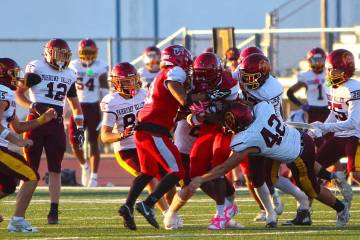 Pahrump Valley’s Christien Ramiscal (42) wraps up a Valley ball carrier as teammates join the ...