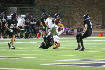 Pahrump Valley’s Lucas Gavenda holds onto the ball as Virgin Valley defenders bring him down ...