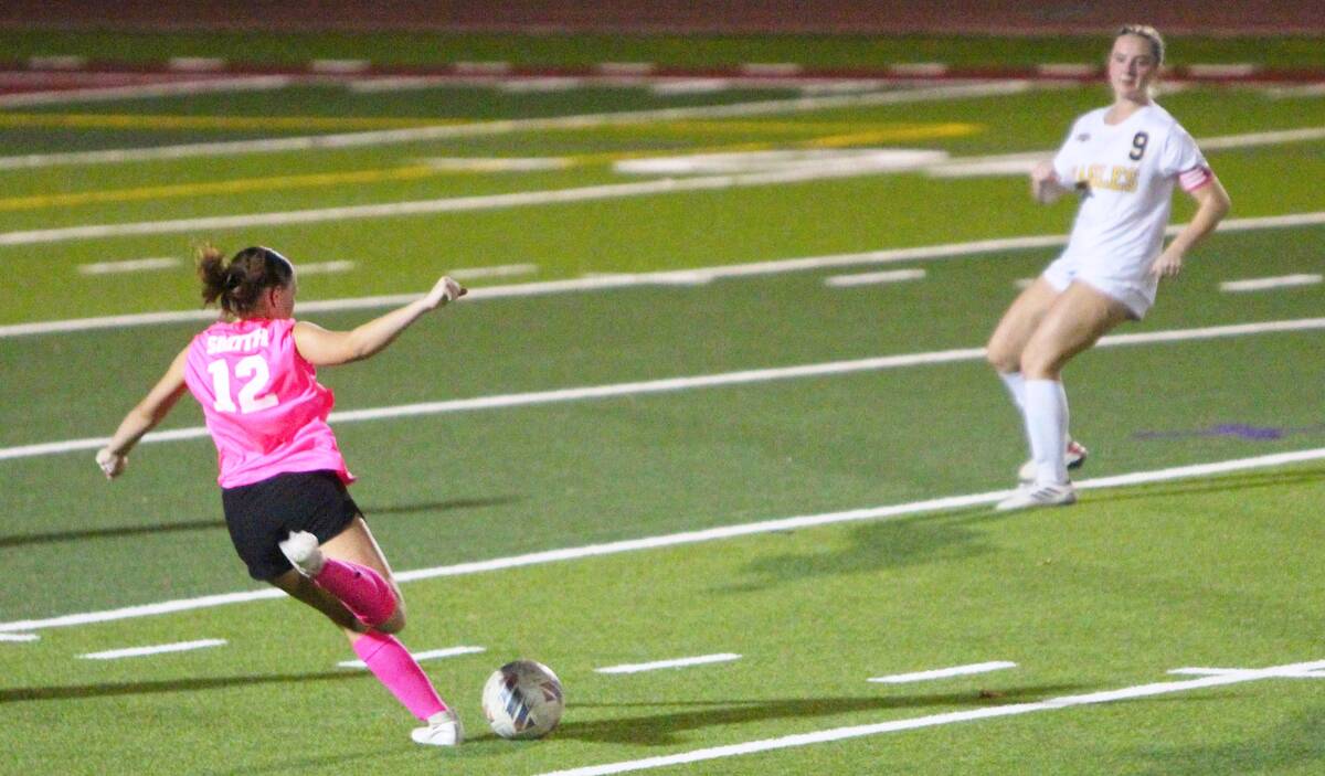 Pahrump Valley’s Raylee Smith (12) prepares to kick the ball as a Boulder City defender appro ...