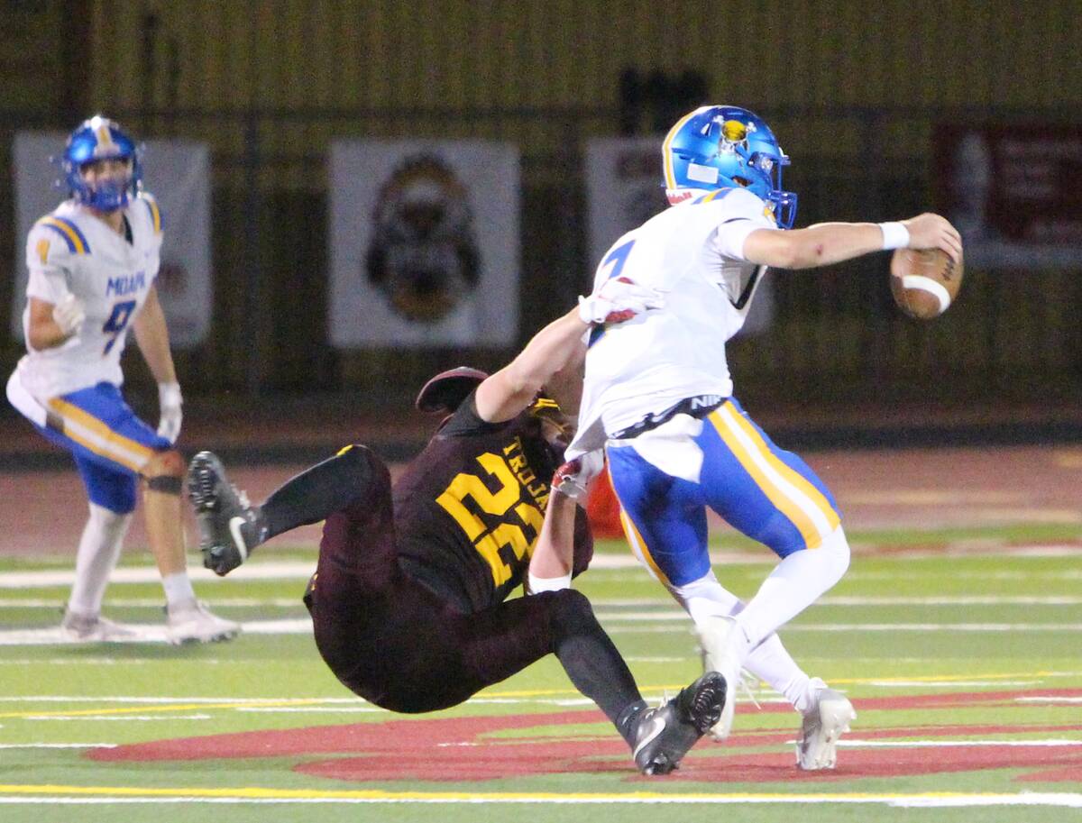 Pahrump Valley’s Paul Walker (22) reaches for Moapa Valley quarterback Kamden Drosos during t ...