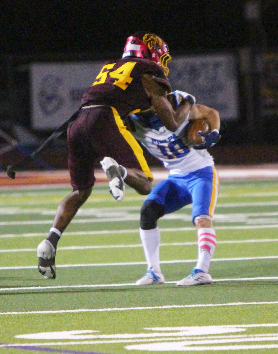 Pahrump Valley’s Iyan Bosket (54) meets a Moapa Valley ball carrier during the Trojans’ Oct ...