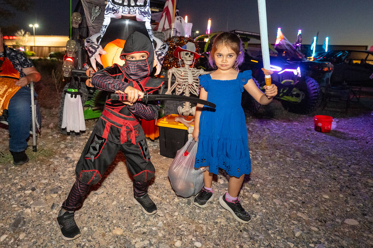 Armed with sword and light saber, two area youngsters take a moment out of the trunk-or-treatin ...