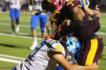 Pahrump Valley’s Angel Ware protects the ball as Moapa Valley defenders wrap him up during th ...