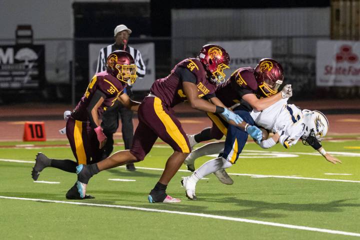 Pahrump Valley’s Paul Walker (22) brings down a Boulder City ball carrier as teammates close ...